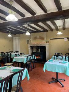 een eetkamer met tafels en stoelen en een open haard bij L'Auberge l'Orée du Bois in Aillières