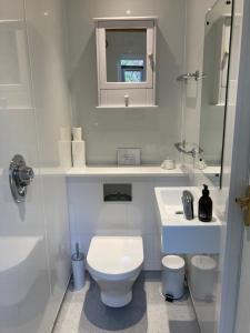 a white bathroom with a toilet and a sink at The Green House in Glenelg
