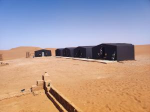 a group of black tents in the desert at Bivouac Le charme d'Aladdin in El Gouera
