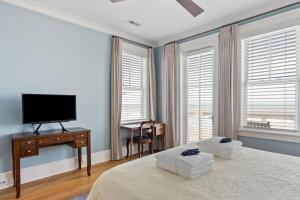a bedroom with a bed and a tv and windows at 1103 E Arctic - Salty Lady - Beautiful Custom Oceanfront Home - Hot tub in Folly Beach
