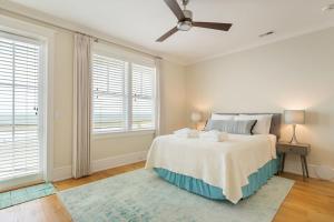 a white bedroom with a bed and two windows at 1103 E Arctic - Salty Lady - Beautiful Custom Oceanfront Home - Hot tub in Folly Beach