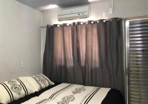 - une chambre avec un lit avec un rideau et une fenêtre dans l'établissement Apartamento Loft encantador com patio, à Foz do Iguaçu