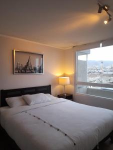 um quarto com uma grande cama branca e uma janela em Alma nova vista al mar em Antofagasta