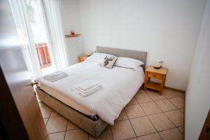 um quarto com uma cama com lençóis brancos e uma janela em Appartamento il Cervo em Fai della Paganella