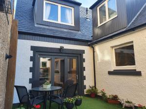 a patio with a table and chairs in front of a house at Maple Cottage B&B in Gullane