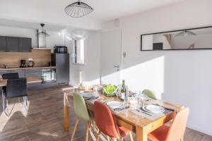 uma sala de jantar e cozinha com mesa e cadeiras de madeira em Gîtes de la Mer - 4 Maisons avec piscine partagée em Erquy