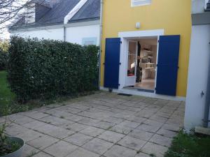 a yellow house with a blue door in a yard at Maison Sauzon, 3 pièces, 4 personnes - FR-1-418-212 in Sauzon