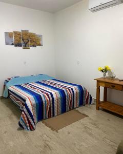 a bed with a striped blanket in a room at Pousada Chalés Praia Vermelha in São João Batista do Glória