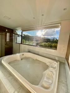 CHALÉS SÓ COISAS BOAS في أورو بريتو: حوض استحمام كبير في حمام مع نافذة