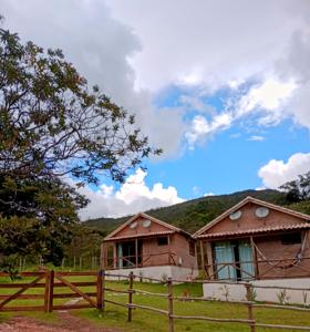 une maison dans un champ avec une clôture en bois dans l'établissement Chalés de Hórus, à São Thomé das Letras