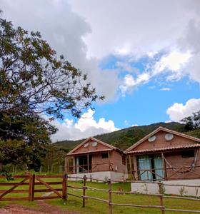 a house in a field with a wooden fence at Chalés de Hórus in São Thomé das Letras