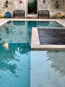a swimming pool with two benches and the water at La Parcela Cunkal in Conkal