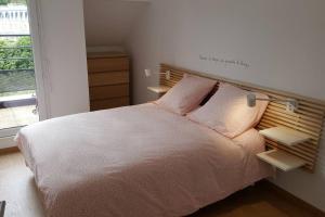 um quarto com uma cama com almofadas cor-de-rosa e uma janela em Kanoperoz-Plage de Trestraou em Perros-Guirec
