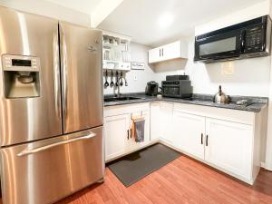 a kitchen with a stainless steel refrigerator and white cabinets at Cute 2-BRM Walkout apt with pool table and theater in Lexington