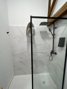 La salle de bains est pourvue d'une douche et d'un sol en marbre blanc. dans l'établissement SUITES CHIC, à Herencia