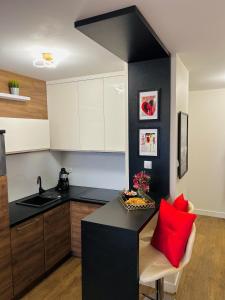 a kitchen with a black counter and a red pillow at Downtown Apartments Presley air-conditioned in Rzeszów