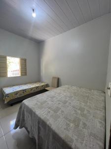 een witte slaapkamer met een bed en een raam bij CASA DE FÉRIAS in Barra do Garças