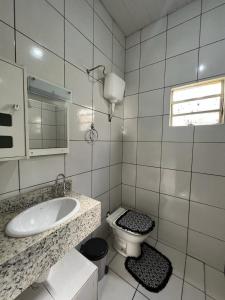 La salle de bains blanche est pourvue d'un lavabo et de toilettes. dans l'établissement CASA DE FÉRIAS, à Barra do Garças