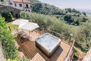 bañera de hidromasaje en una terraza de madera con sombrilla en Holiday Home Il Borgo Degli Agrumi, en Uzzano