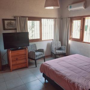 1 dormitorio con 1 cama y TV de pantalla plana en El descanso, zona de bodegas en Luján de Cuyo