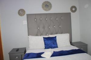a bedroom with a bed with blue and white pillows at El Rose Guest House in Rustenburg