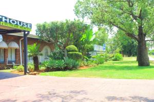 a building with a sign in front of a yard at El Rose Guest House in Rustenburg