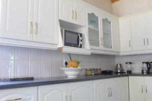 a kitchen with white cabinets and a bowl of fruit on the counter at El Rose Guest House in Rustenburg