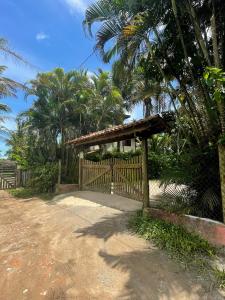 a wooden fence in front of a house with palm trees at Aldeia de Camburi in Camburi
