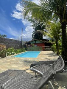 einen Stuhl neben einem Pool mit einer Palme in der Unterkunft Aldeia de Camburi in Camburi