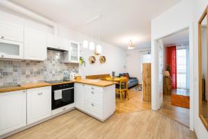 a kitchen with white cabinets and a dining room at Metro Bemowo Colourful Apartment in Warsaw