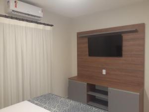 a bedroom with a flat screen tv on a wall at Lençóis Confort Barreirinhas in Barreirinhas