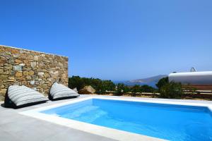 a swimming pool with pillows next to a stone wall at Sea Breeze Mykonos in Mykonos