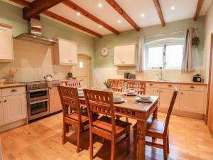 a kitchen with a wooden table and wooden chairs at High Trees in Sandbach