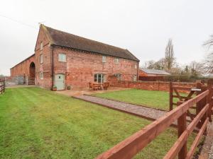 an old brick barn with a grass yard in front of it at High Trees in Sandbach