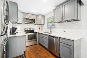 a kitchen with stainless steel appliances and white cabinets at Stunning & Vibrant APT 7 Min From TX Med Center in Houston