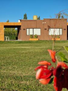 una casa con un edificio en el fondo con flores rojas en Cabañas Bodega 1920 en San Rafael