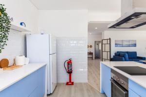 uma cozinha com armários azuis e um frigorífico branco em DORA'S HOME em Cacilhas