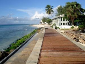 un paseo marítimo que conduce a una playa con una casa en 1B Hastings Towers en Bridgetown