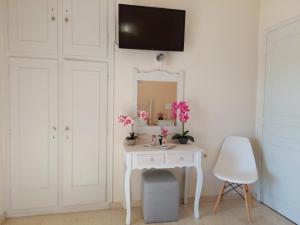 tocador blanco con espejo y silla blanca en Panayota Apartments, en Kassiopi