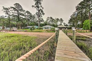 a wooden bridge over a field with trees in the background at Sunset Cottage on Paukie Island with Private Dock! in Beaufort