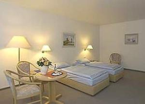 オルデンブルクにあるStadthotel Oldenburgのベッド2台、テーブルと椅子が備わるホテルルームです。