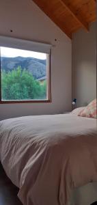 a bedroom with a large bed and a window at Mirador del Bosque Aparts in El Chalten