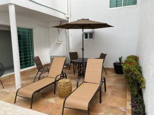 a patio with a table and chairs and an umbrella at Casa boka con vista al mar y alberca in Boca del Río