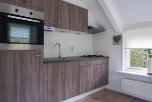 een keuken met houten kasten, een wastafel en een raam bij Vakantie huis Ermelo in Ermelo