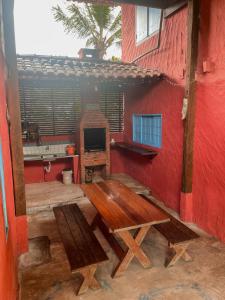 een patio met een houten tafel en een rode muur bij Aldeia de Camburi in Camburi