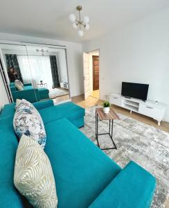 ein blaues Sofa im Wohnzimmer mit einem TV in der Unterkunft Maxx Suites Cluj Napoca in Cluj-Napoca