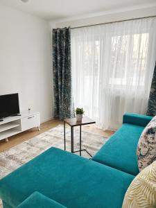 ein Wohnzimmer mit einem blauen Sofa und einem TV in der Unterkunft Maxx Suites Cluj Napoca in Cluj-Napoca