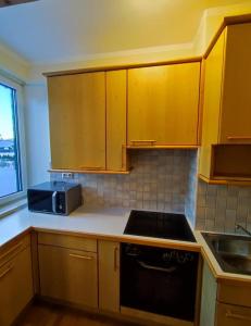 a kitchen with wooden cabinets and a black stove top oven at Apartment inklusive Parkplatz in Velden am Wörthersee
