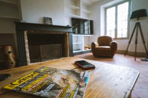 ein Wohnzimmer mit einer Zeitschrift auf einem Tisch und einem Kamin in der Unterkunft Bleausard’s Guest House, cozy place next to river in Grez-sur-Loing