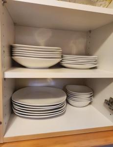 a stack of plates and bowls sitting on a shelf at Apartment inklusive Parkplatz in Velden am Wörthersee